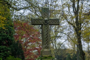 Celtic cross standing in a cemetery during autumn