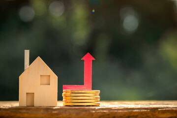 Home model and red arrow graph with growing value put on the gold coin put on the wood in the...