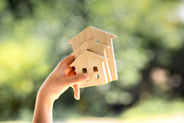 Man hand hold for select the three home model on sunlight building background, Loan for real estate or saving money for buy a new house to family in the future concept.
