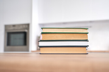 Stacked books on wooden kitchen counter with modern oven in background focusing on education and home design.