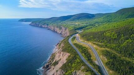 Aerial view of a scenic coastal highway winding through a green landscape with blue ocean and sky.