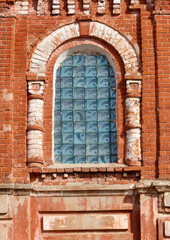 A window with a blue glass pane in a brick building
