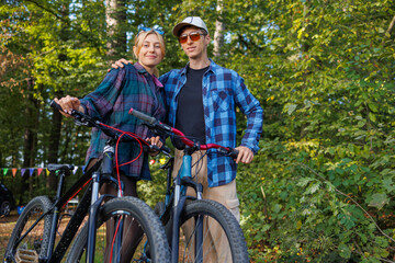 Naklejka premium Portrait of a young couple man and woman with bicycles in the forest