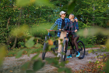 Obraz premium A young man hugs a girl while standing in nature while riding a bike