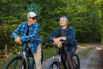 Obraz premium Happy young couple enjoying cycling through the forest