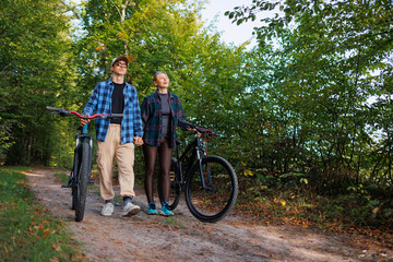 Obraz premium Young man and a woman walk in nature with bicycles after riding