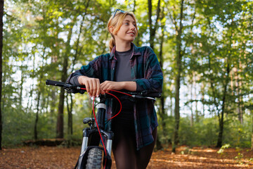 Portrait of a young woman with a bicycle in the forest