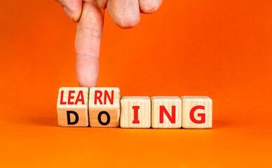 Doing or learning symbol. Businessman turns wooden cubes and changes the word Doing to Learning . Beautiful orange table orange background. Educational business doing or learning concept. Copy space.