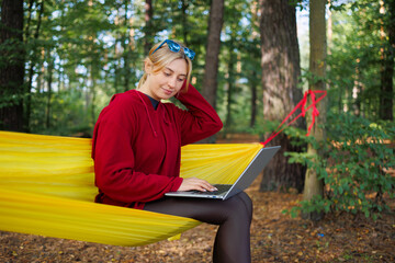 Girl with a laptop on a hammock in the forest