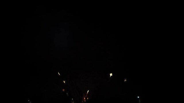 red blue and lilac sparks scattering fireworks on the black night sky above the city. General plan