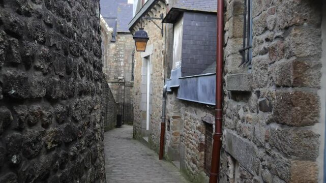 A walk through the narrow, charming streets within Mont-Saint-Michel, France, featuring historic buildings and a unique medieval atmosphere.