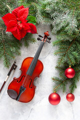 Old violin and fir-tree branches with Christmas decor and poinsettia. Christmas and New Year's concept. Top view, close-up