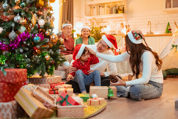 christmas, family, celebrating, enjoying, celebrate, enjoyment, parents, celebration, laughing, parent. A family is gathered around a Christmas tree. Scene is warm and festive.