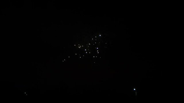gold lilac blue green sparks scattering fireworks on the black night sky over the city. General plan