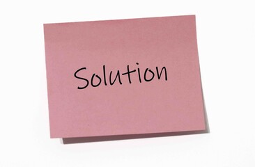Pink Sticky Note with the Word "Solution" Written in Black Handwriting on a White Background