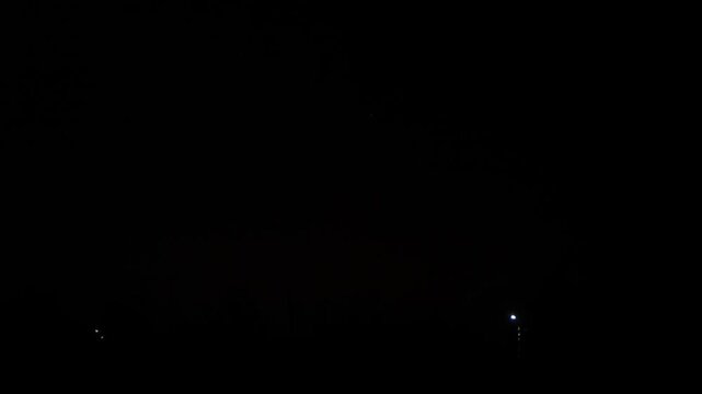 gold red green sparks scatter fireworks on the black night sky over the city. General plan