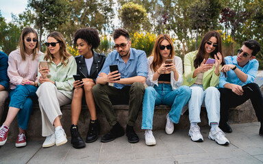 Diverse young people friends using smartphones together outdoors social media technology lifestyle modern generation connection