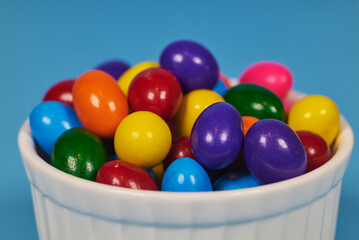 Chewing gum balls of different colors in shiny earthenware containers with a homogeneous colored background for placing text