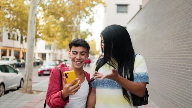 Happy latin couple using smartphone on city street