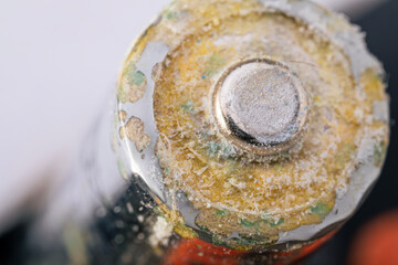 Corroded battery with visible leakage and damage on metal surface. Macro shot.
