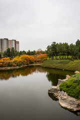 multi-storey modern house in autumn park, reflection in water, architecture, lake, yellow leaves of trees