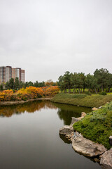multi-storey modern house in autumn park, reflection in water, architecture, lake, yellow leaves of trees