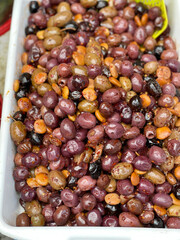 Pickled olives with spices in different colors in containers and buckets at market in Europe, Italy. Organic local food and health. Seasonal vegetables.