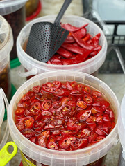 Pickled peppers with spices in scooped buckets at market in Europe, Italy. Organic local food and health. Seasonal vegetables.