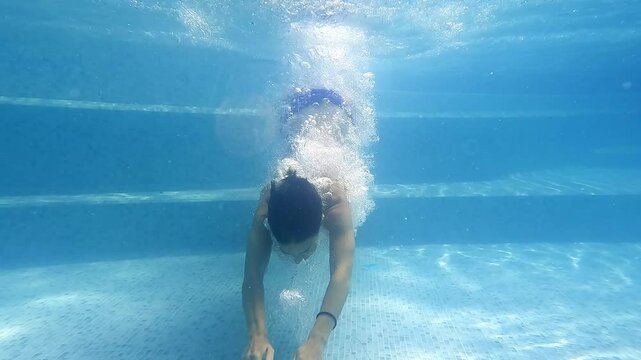 A woman swims underwater in a pool on a warm summer day. Relaxation, spa and vacation concept.