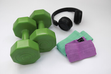 dumbbell on a white background.home workout concept. dumbbells, rubber bands and headphones lie on...