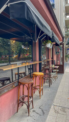 Charming urban cafe with a street-side view, featuring classic high stools and wooden countertops under a protective awning, ideal for city lifestyle and leisure themes in marketing