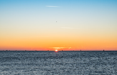 Magical Fiery Sunset on the Sea in Winter: Light Trails and Birds in Flight Painting the Sky. Grado, Italy.