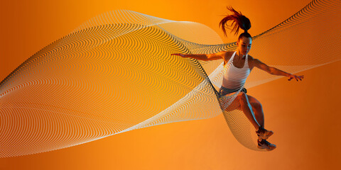 Young athletic woman, runner in motion, jumping, training against orange background with abstract...