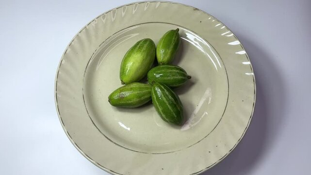 Pointed gourd rotating on a plate with white background, 4K