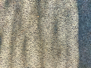 Textured surface with distinct patterns created by shadows during daylight in an outdoor setting