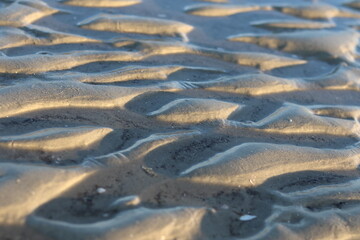 A pattern of sand and water on the beach created by the sun during sunrise