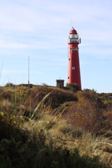 Red lighthouse on the island of Schiermonnikoog, with dunes and marram grass in the foreground