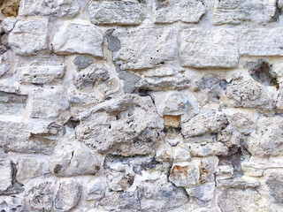 Detailed view of an ancient stone wall featuring weathered textures and varying colors in an outdoor setting