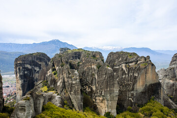 Meteroa, Greece. Majestic rock formations in rise dramatically from the landscape, offering a glimpse into nature's grandeur against the backdrop of distant snow-capped mountains