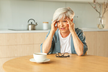 Headache pain. Unhappy middle aged senior woman suffering from headache sick rubbing temples at...