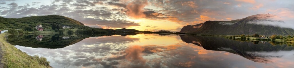 Panoramic view of Norway's Lofoten Islands under the midnight sun. Golden light illuminates...