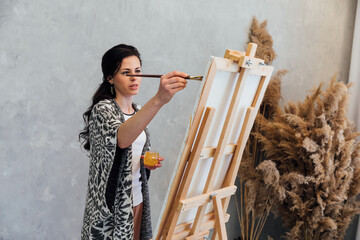 Female artist painting paintings with paints on canvas with easel