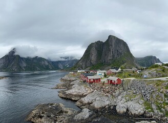 Red Rorbuer cabins on Norway's Lofoten Islands, set against stunning mountains and the Arctic sea&mdash;capturing the charm of Nordic coastal life.