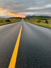Fototapeta premium Panoramic view of Norway's Lofoten Islands under the midnight sun. Golden light illuminates mountains, coastlines, and calm waters, showcasing the stunning beauty of the Arctic summer landscape