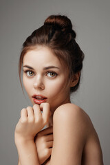 Beautiful young woman posing with her hands on her chin, lips parted, and eyes looking off to the side