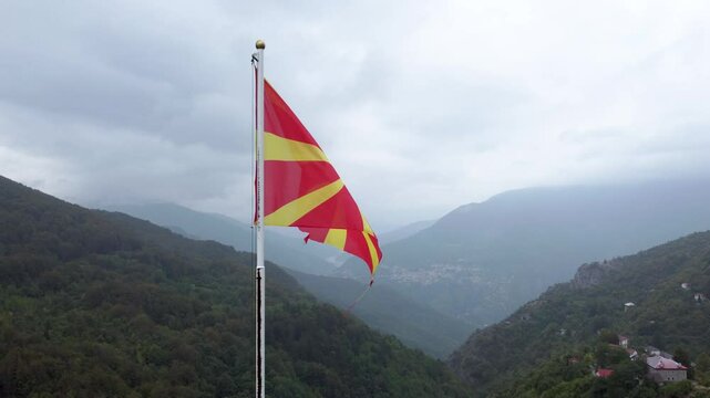 Flag of North Macedonia. National flag on flagpole, aerial drone view. Yellow sun on red field. 