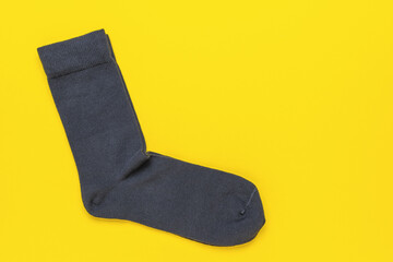 Single Black Sock on Vibrant Yellow Background Showcasing Minimalist Fashion Concept