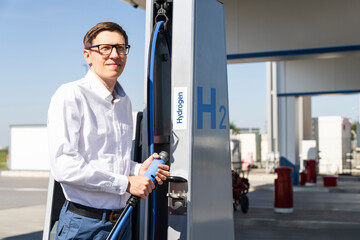 Man holds a hydrogen fueling nozzle on a hydrogen filling station. Refueling car with hydrogen fuel.