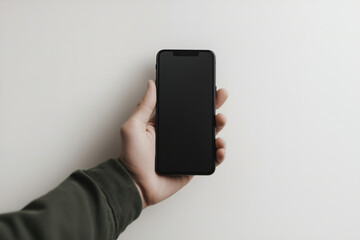 A person holding a black smartphone against a plain white wall in a well-lit indoor setting during the daytime. Generative AI