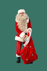 Santa Claus putting parcel into gift bag on green background